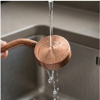 Copper showerhead arm being rinsed during drip coffee maintenance